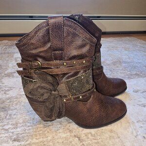 Brown boots with brass detailing and lace bow.